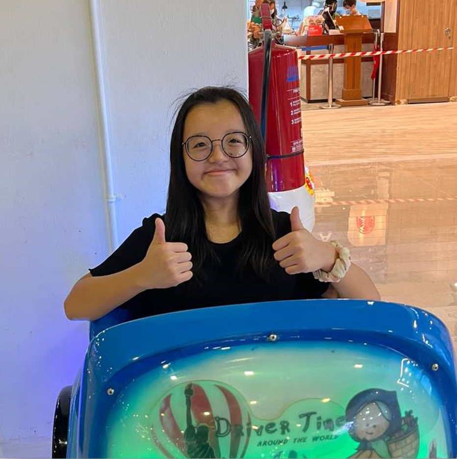 Magdalene smiling and giving 2 thumbs up