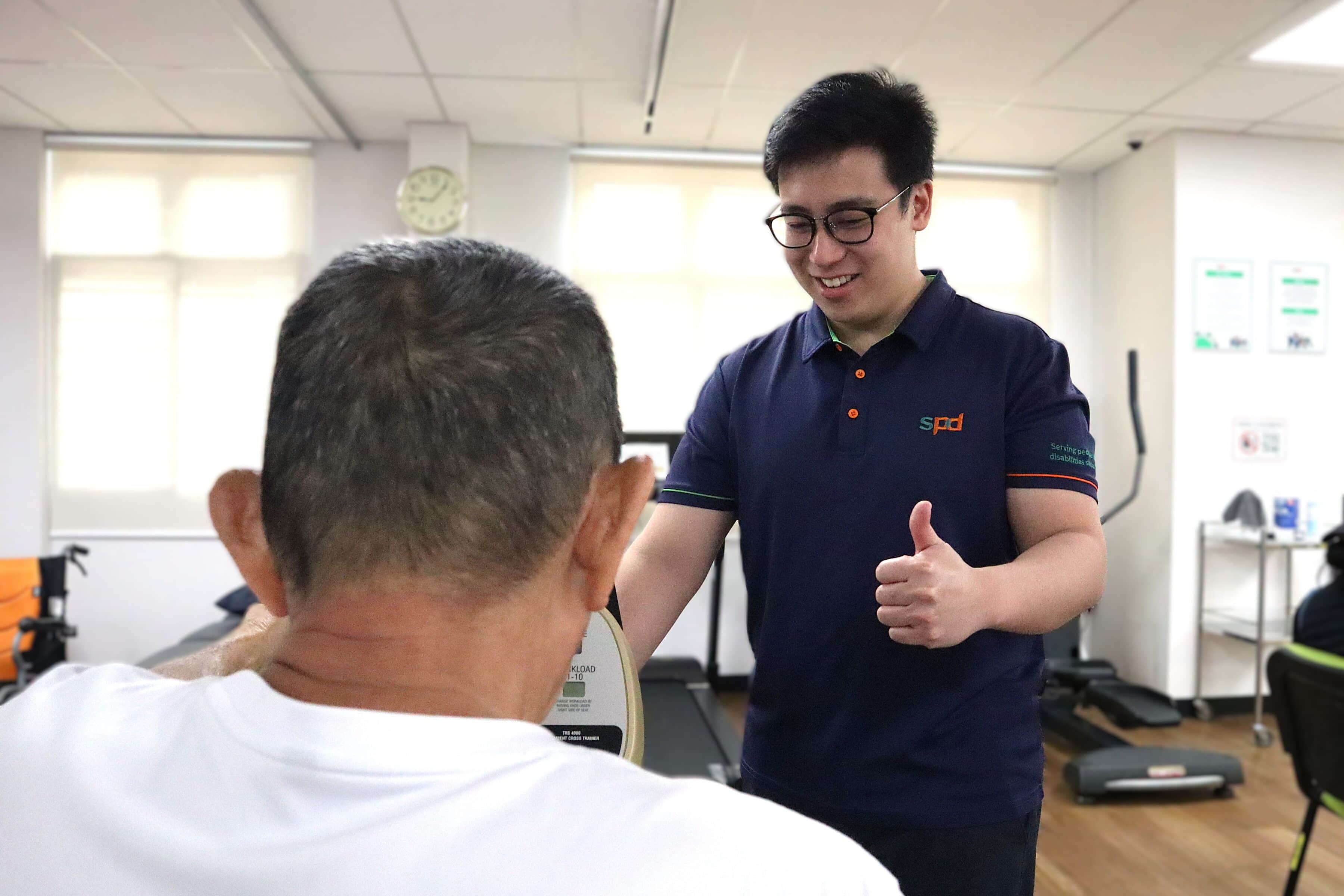 Joel encouraging a senior on a rehab equipment.