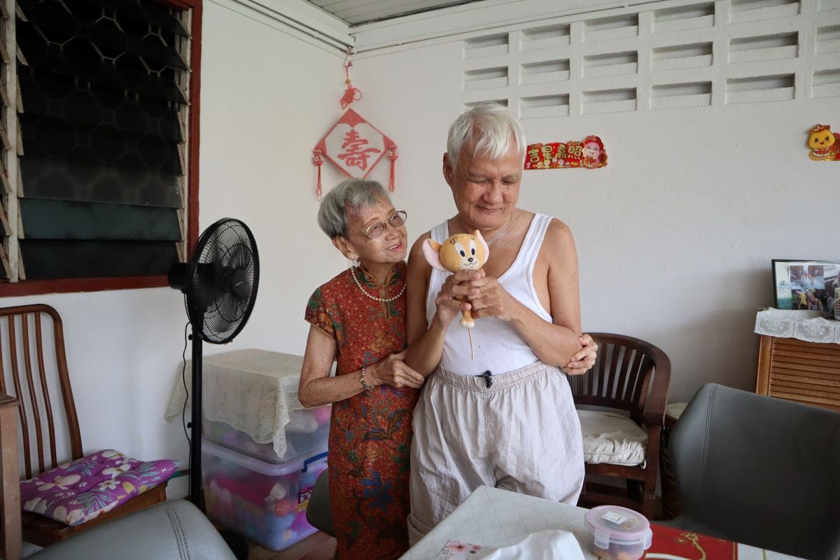 Auntie with her arm around her youngest son Mr Lee, who is holding up a small soft toy.