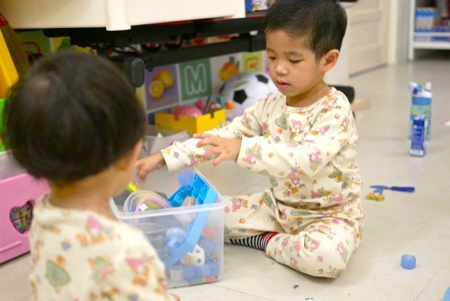 2 boys in pyjamas playing with toys out of a box