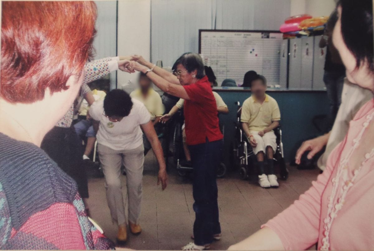 An old photo of Auntie Molly at the D A C playing 'London Bridge is Falling Down' with the clients.