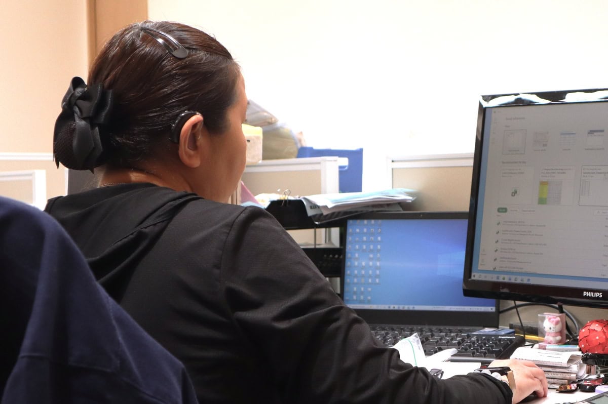 A person wearing a hearing aid looking at a computer screen