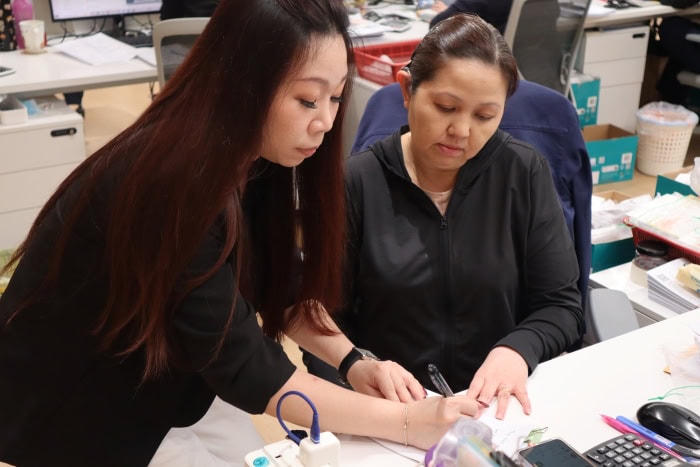 Ms Samantha Lin communicating with Ms Julia Poh by writing on paper