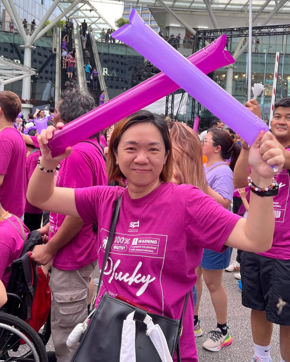 Alexis in the SPD contingent holding up 2 inflatable clappers at the Purple Parade