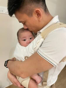 Bradley hugging baby daughter in his arms in baby carrier